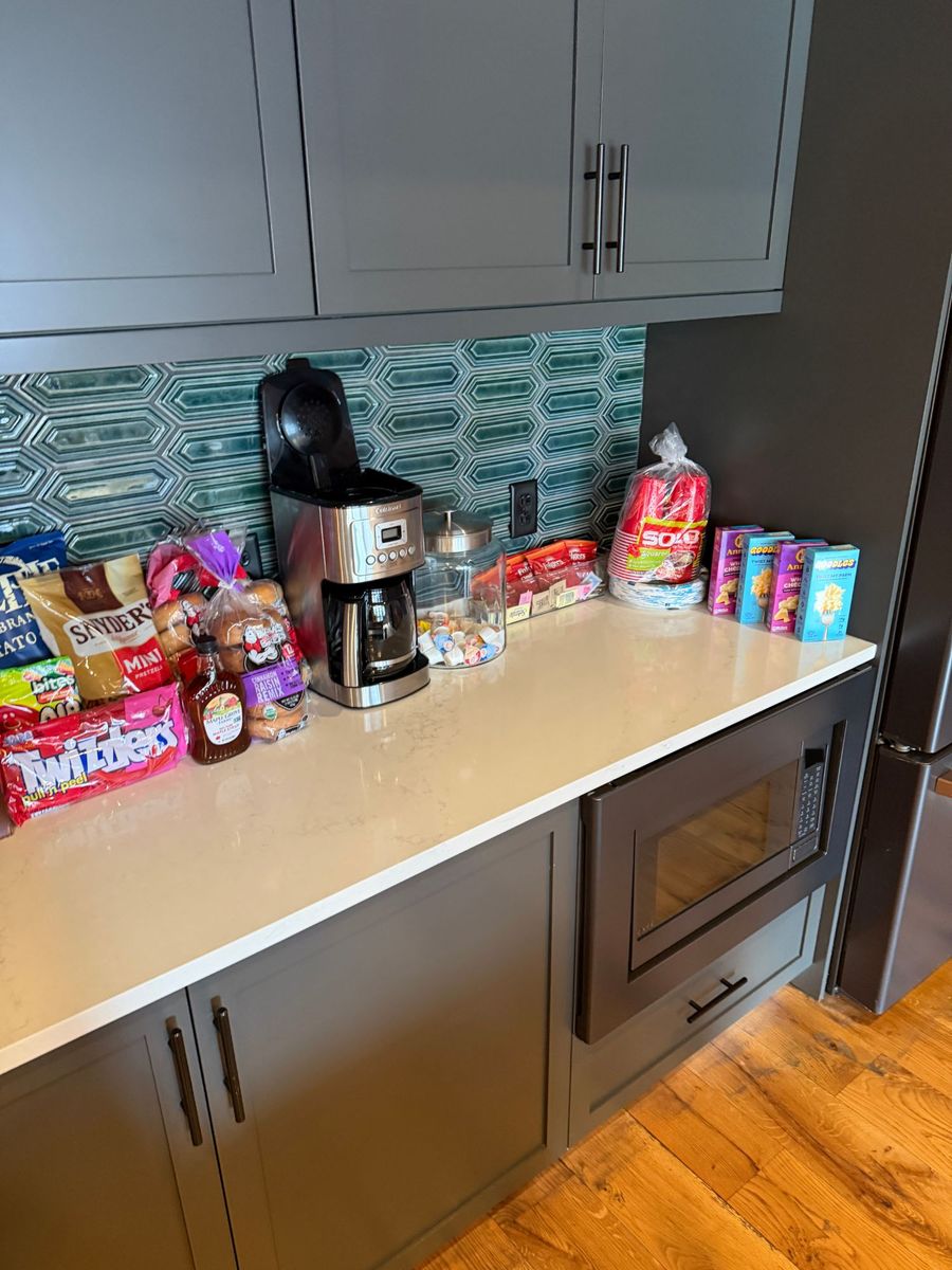 Snacks, a coffee maker and boxes staged on a kitchen counter above a built-in microwave